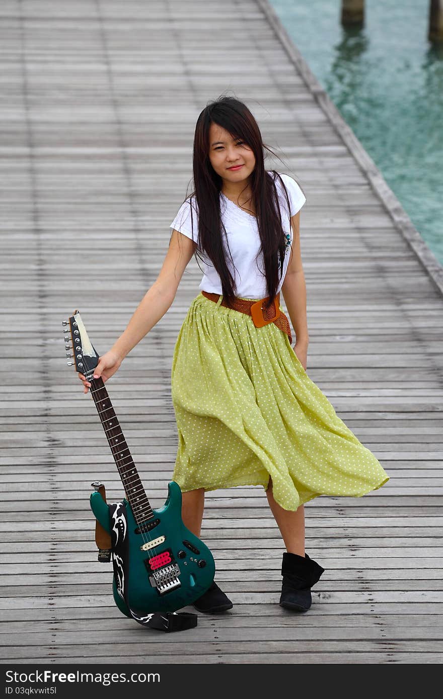 Young pretty woman with guitar on bridge