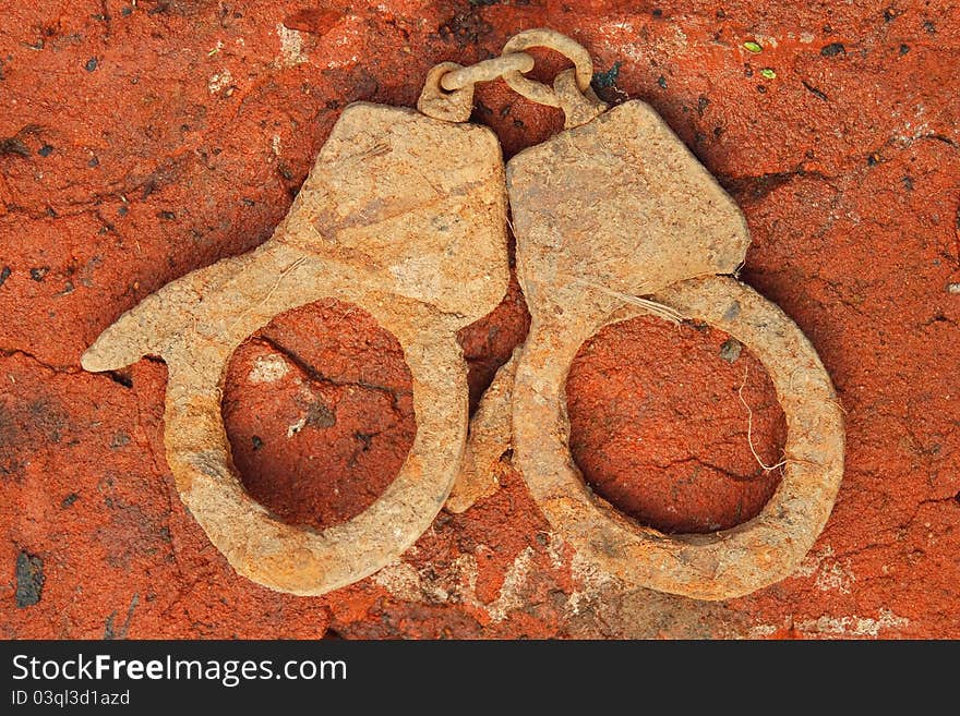 The old, rusted, metal handcuffs on the brick floor. The old, rusted, metal handcuffs on the brick floor