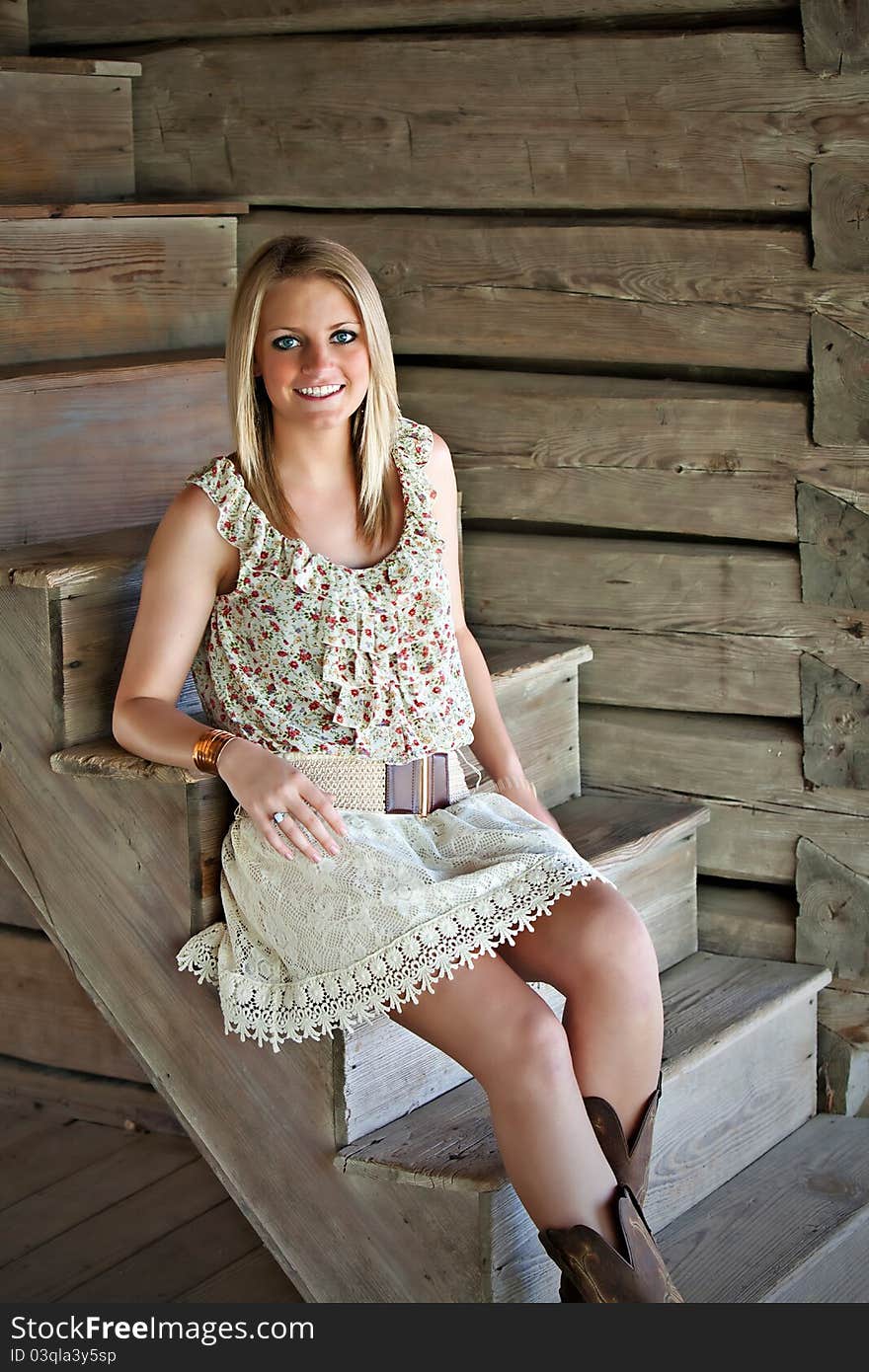 Portrait of beautiful smiling teenage girl sitting next to a log wall. Portrait of beautiful smiling teenage girl sitting next to a log wall.