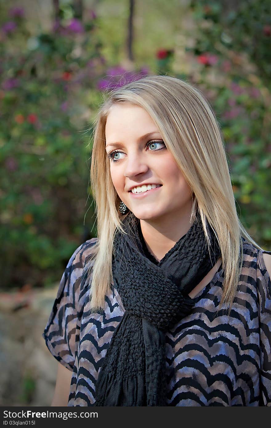 Portrait of beautiful smiling teenage girl standing next to a flower garden. Portrait of beautiful smiling teenage girl standing next to a flower garden.