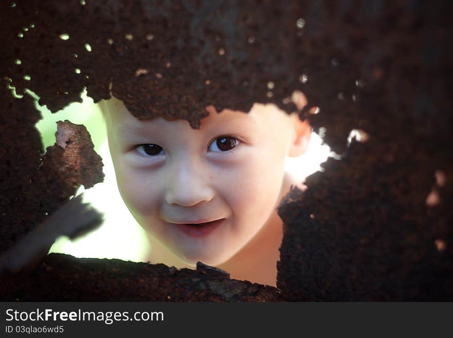 Funny baby hiding behind rusty old steel