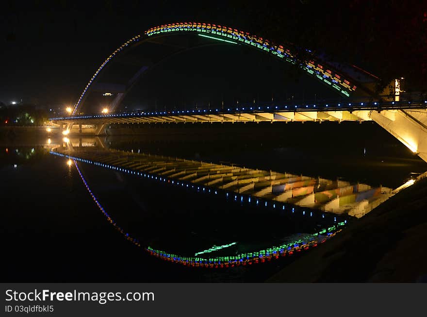 Illuminated bridge in the night reflected in still river. Illuminated bridge in the night reflected in still river