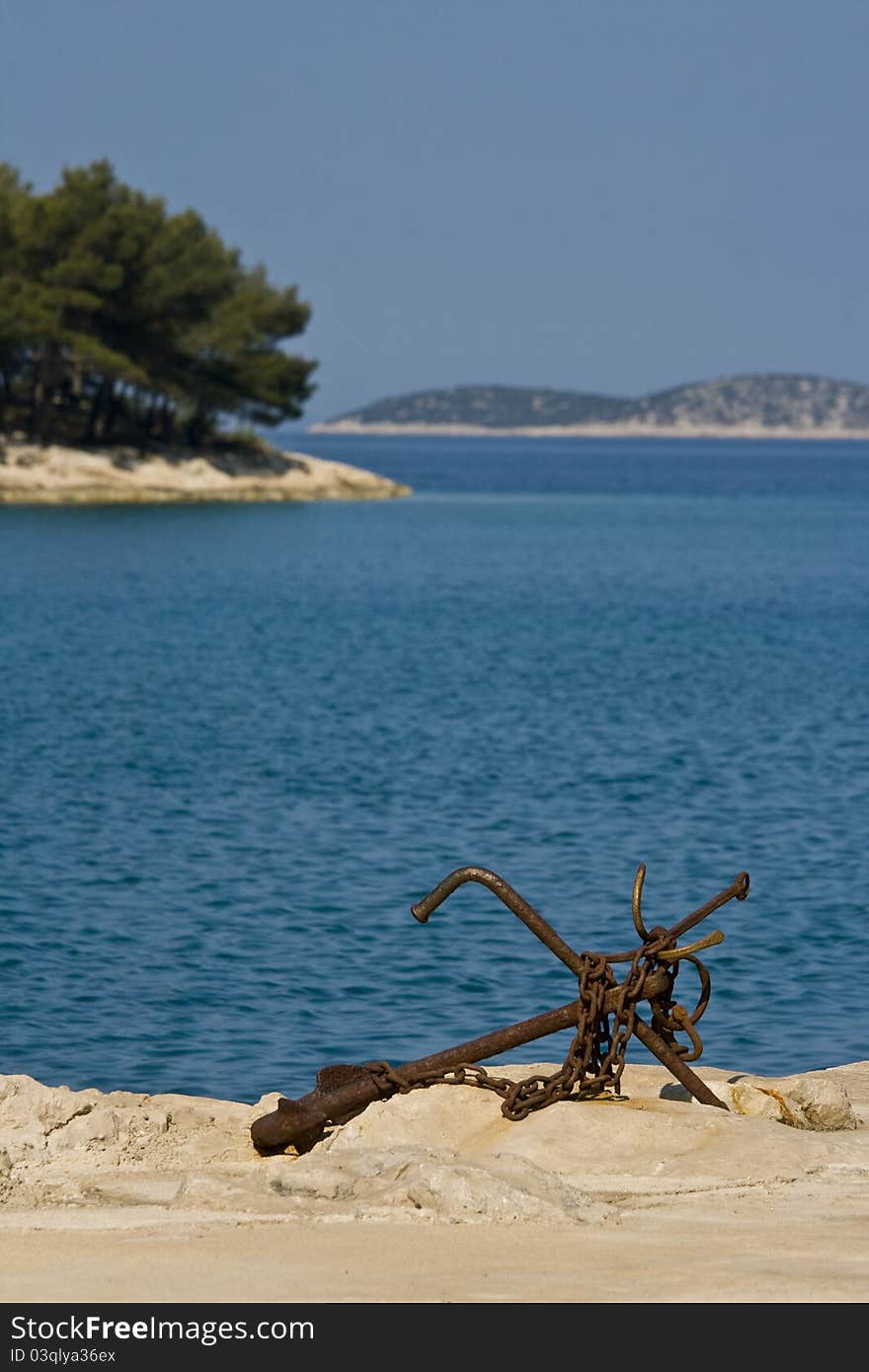 Old rusty anchor on the rocky coast of Tribunj. Old rusty anchor on the rocky coast of Tribunj