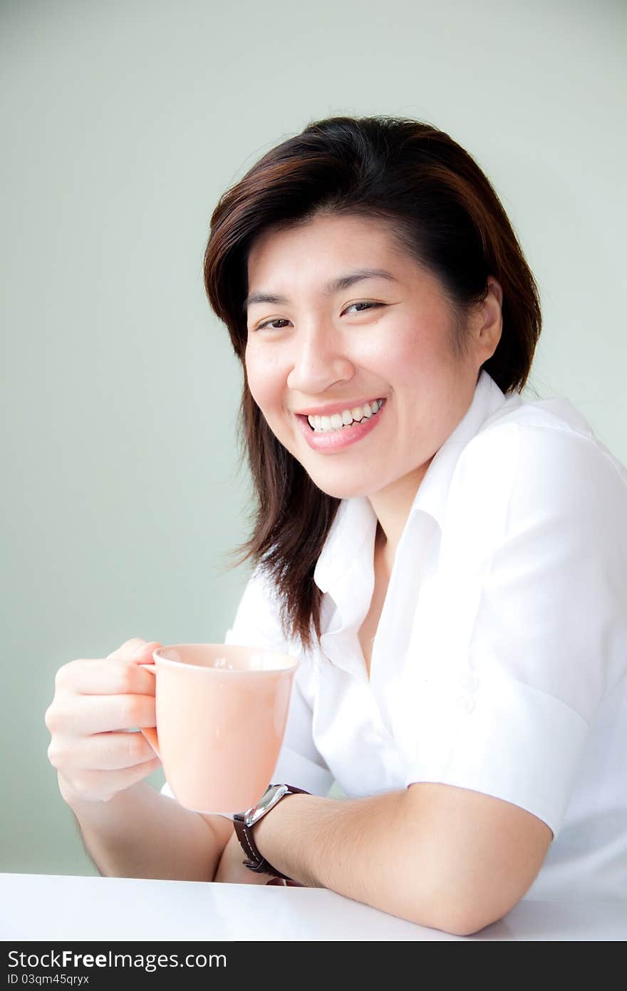 Smiling young asian woman holding a cup