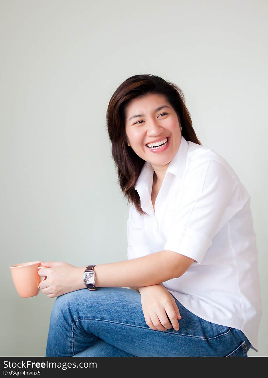 Smiling young asian woman holding a cup