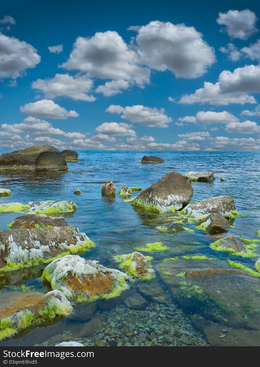 Stones into the sea on sunny sky background