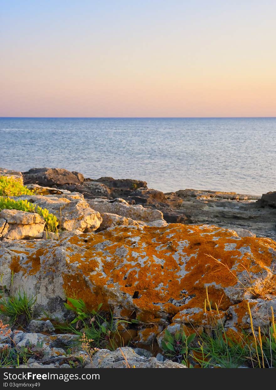 Stones into the sea on sunny sky background