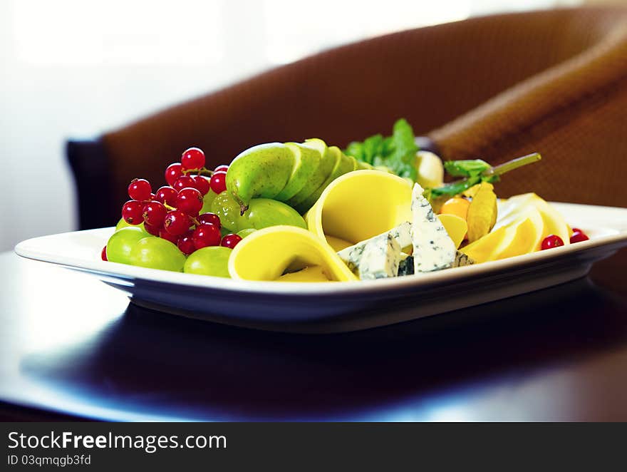 Various types of cheese, grapes and redcurrant close-up composition