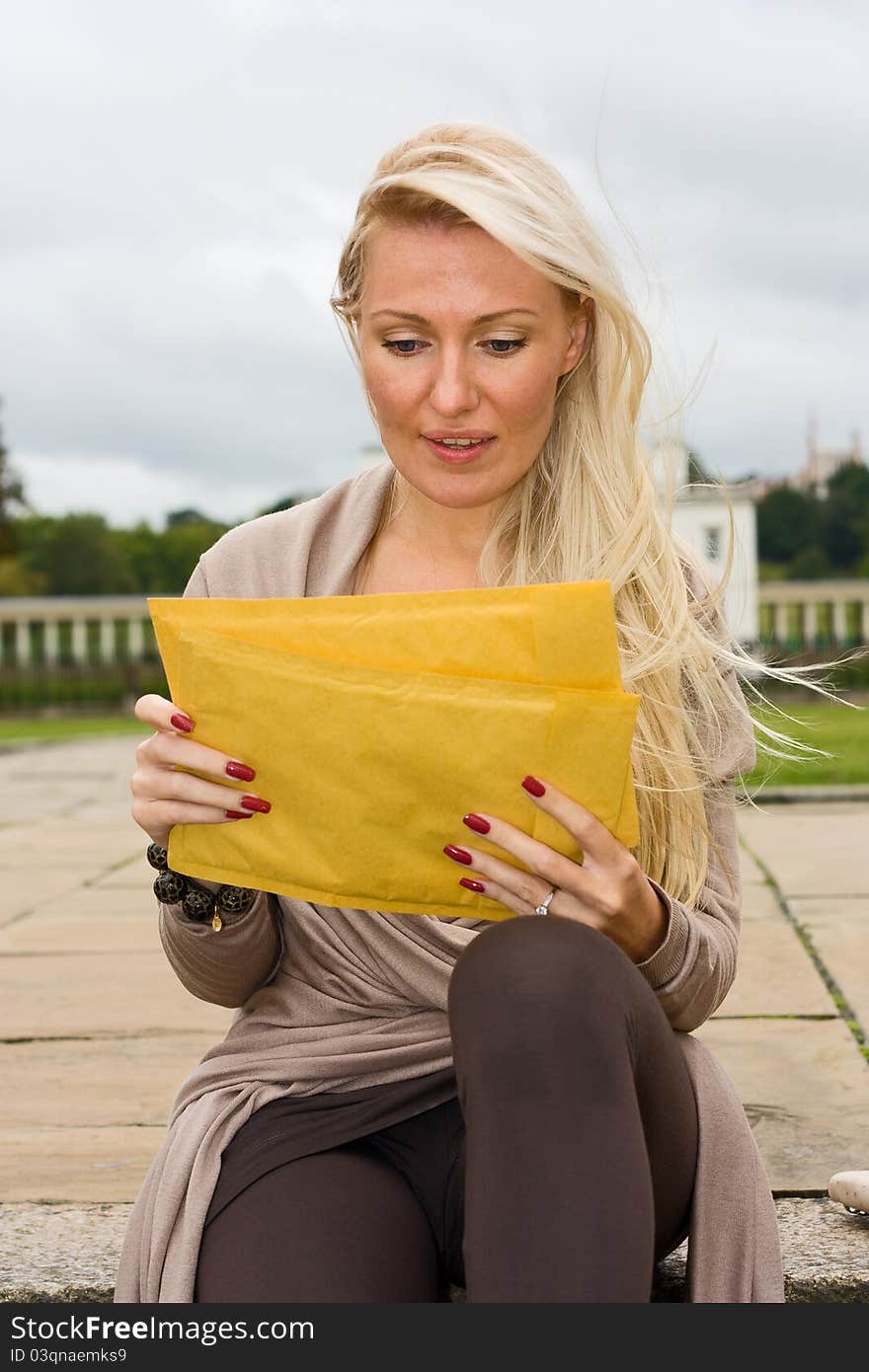 A woman sitting down reading her post. A woman sitting down reading her post.