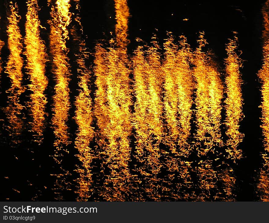 An abstract image of fiery looking lights reflected on a flowing river. An abstract image of fiery looking lights reflected on a flowing river.