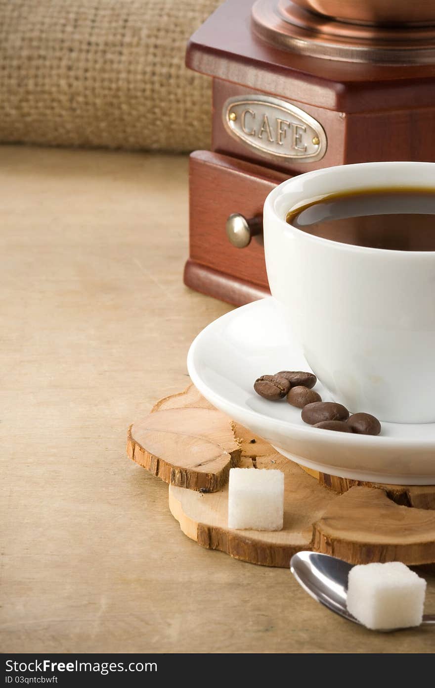 Cup of coffee and grinder with roasted beans