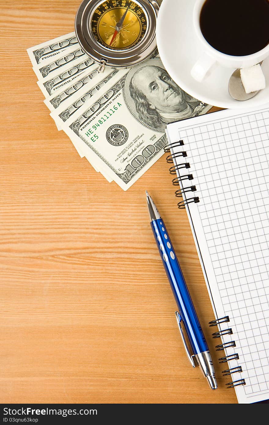 Notebook and coffee with dollar on wood table