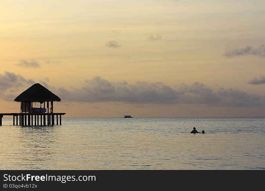 A hut on stilts at sunset in the Maldives