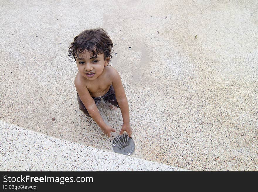 Happy toodler boy playing water park fountain