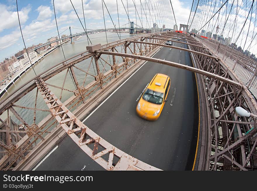 Wide angle photo of a yellow taxi on Brooklyn Bridge, New York