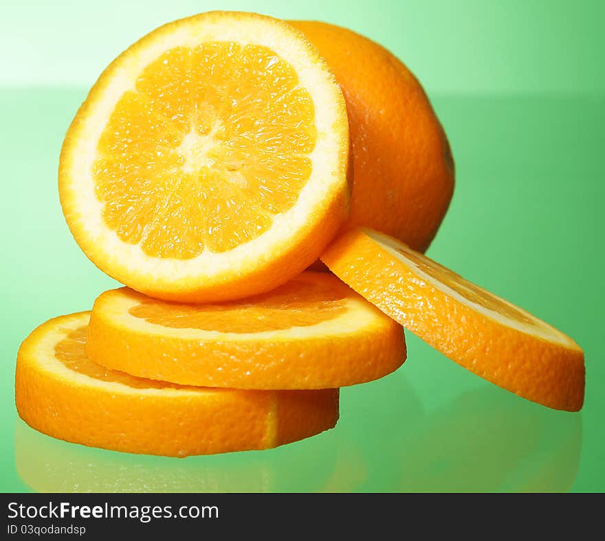 Orange and orange slices on green background.