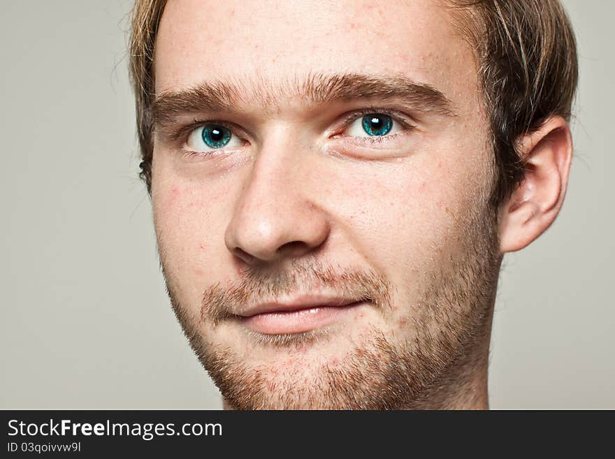 Young blond man with blue eyes on gray background looking confident. Young blond man with blue eyes on gray background looking confident