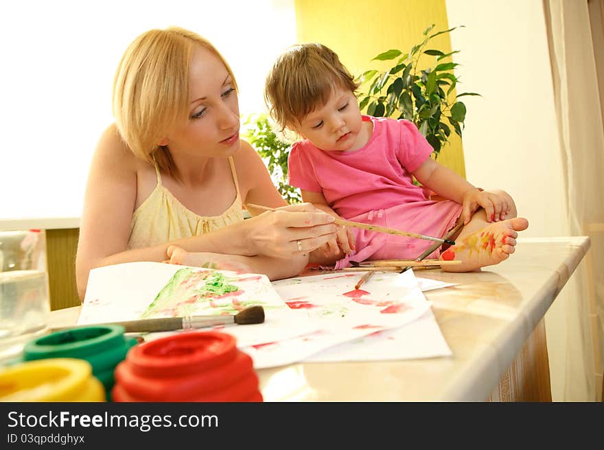 Mother drawing a flower on her daughter heel. Mother drawing a flower on her daughter heel