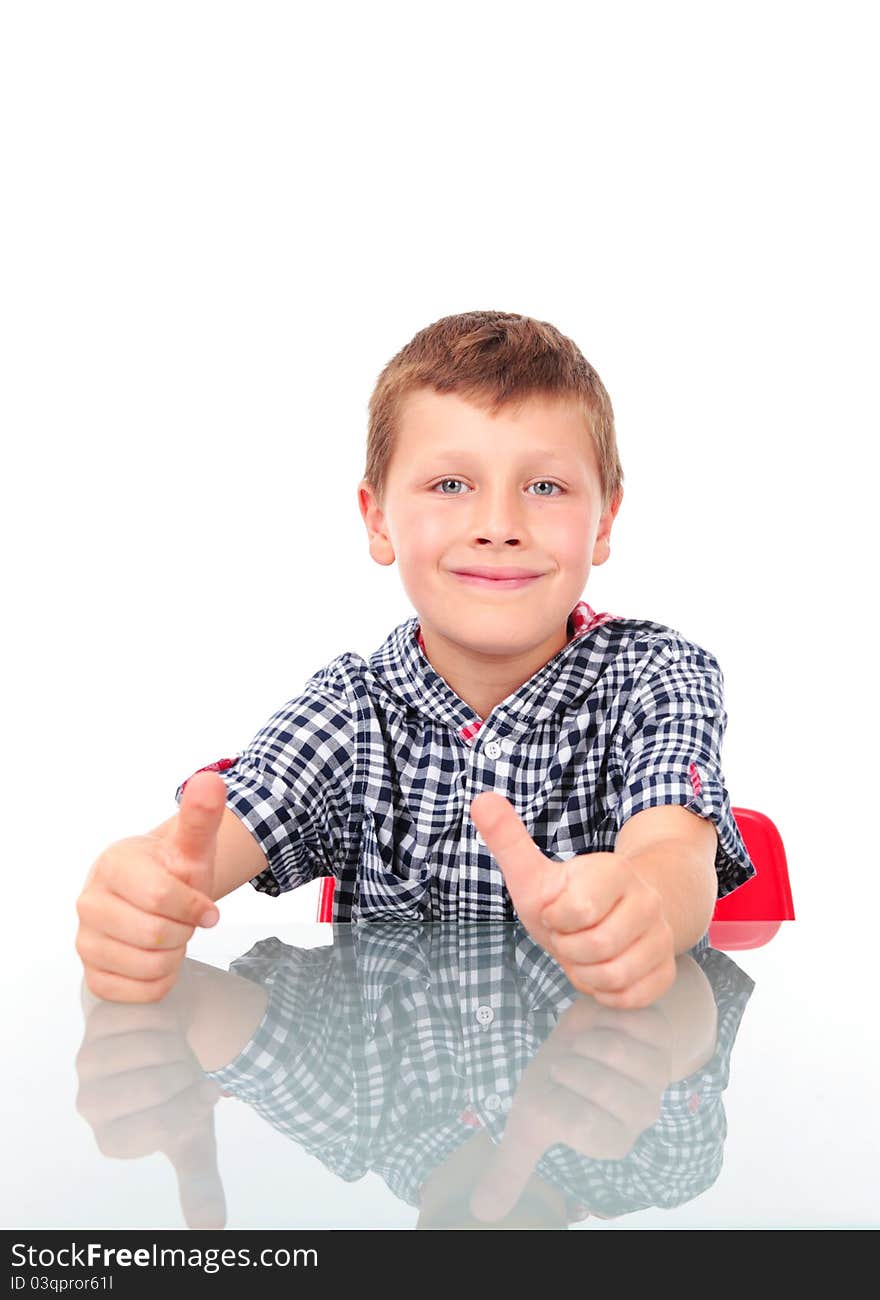 Young boy sitting near table and showing OK sign. Young boy sitting near table and showing OK sign