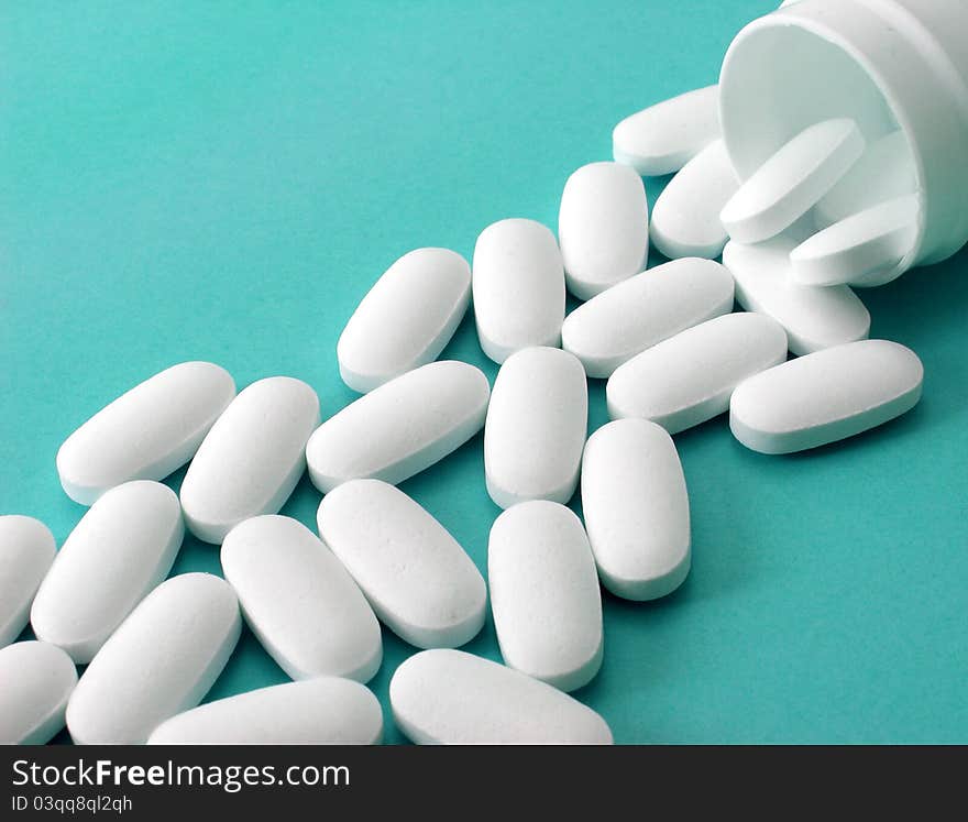 Many white pills on blue background