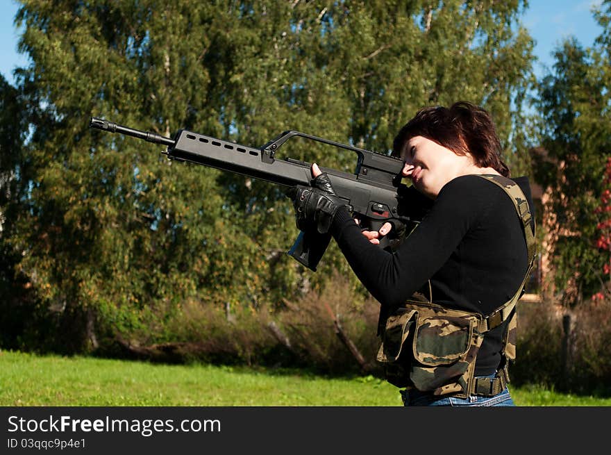 Beautiful girl with a gun to airsoft outdoors