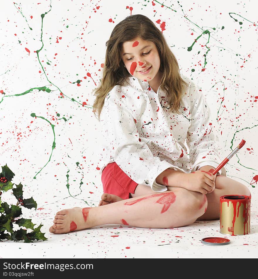 An attractive preteen surrounded by splattered red and green paint looking at that which is on herself. An attractive preteen surrounded by splattered red and green paint looking at that which is on herself.