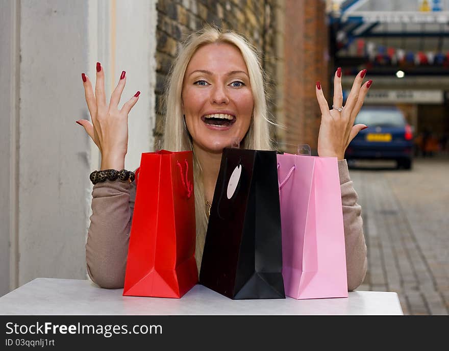 Excited woman with shopping bags sitting outside a cafe. Excited woman with shopping bags sitting outside a cafe.