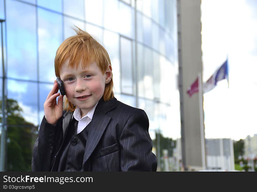 Smart boy talking by phone in front of an office building. Smart boy talking by phone in front of an office building