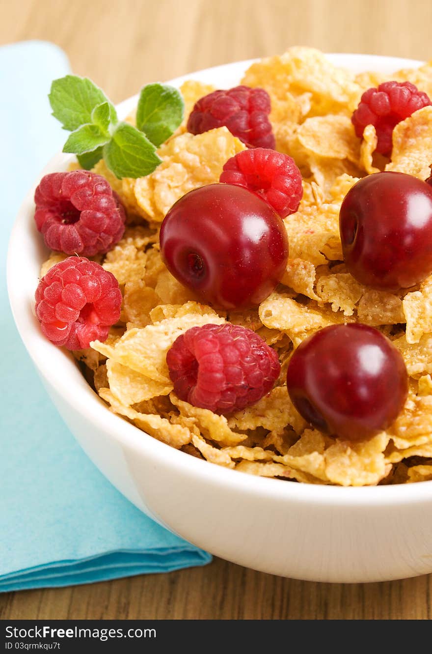 Plate of corn flakes with raspberries and cherries. Plate of corn flakes with raspberries and cherries