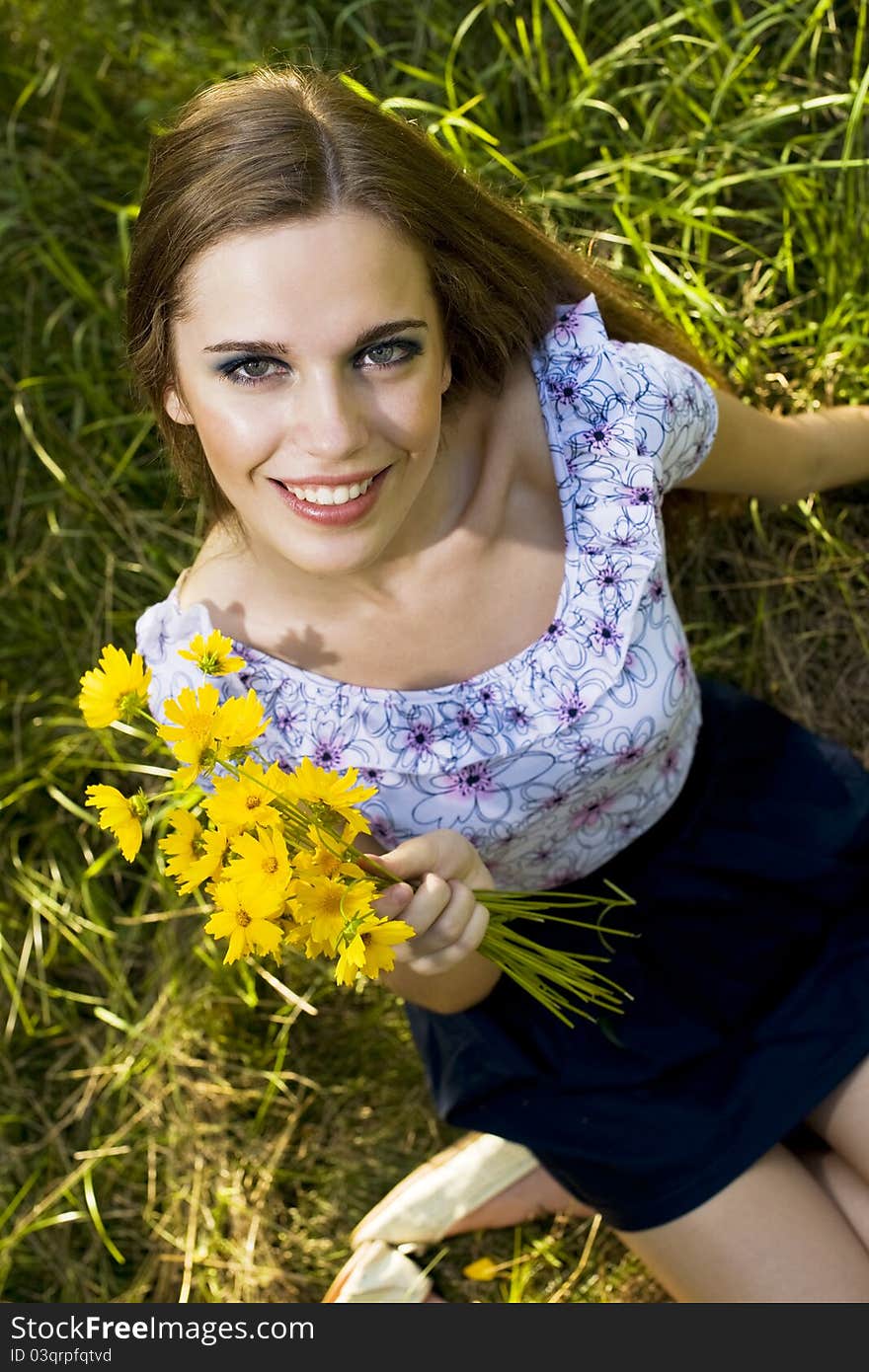 Portrait of a happy young girl smiling and holding orange flowers in her hands outdoor in summertime