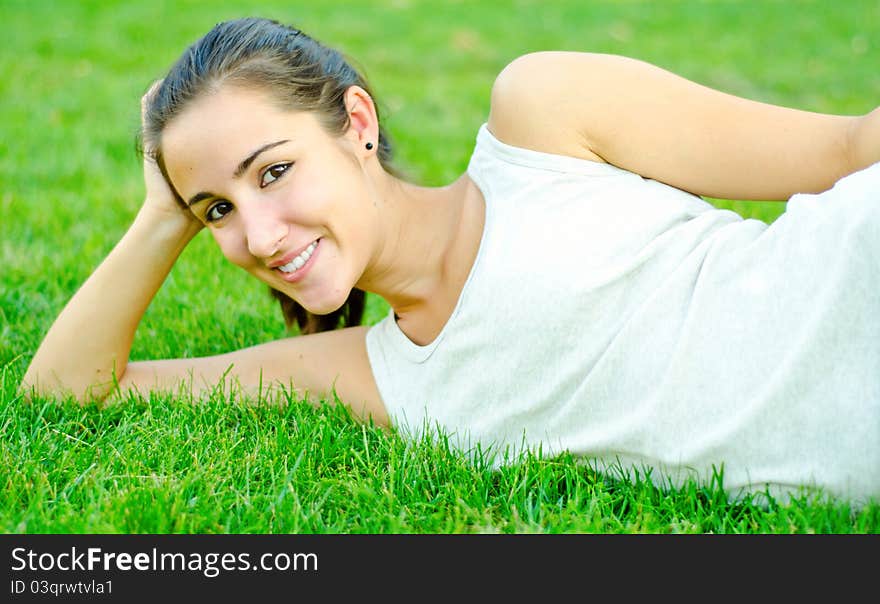 Young girl resting on grass smiling beautifully. Young girl resting on grass smiling beautifully