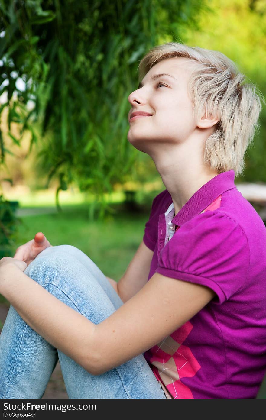 Pretty smiling girl alone sitting on the bench in the park. Pretty smiling girl alone sitting on the bench in the park