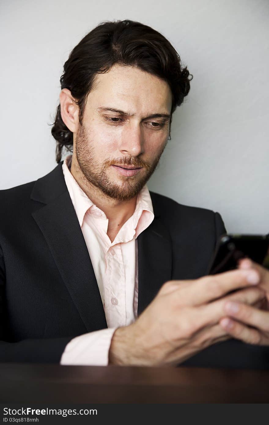 Young businessman sending an sms from his mobile phone. Young businessman sending an sms from his mobile phone