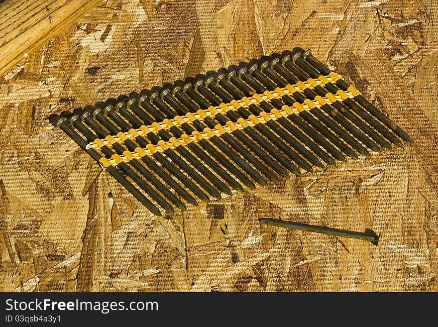 Row of gun nails on a plywood background.