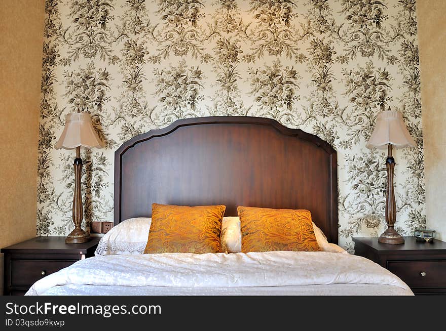 Bedroom with flowery pattern wall paper and wooden furniture, in classical color, shown as nature, classical, and comfortable living environment in home. Bedroom with flowery pattern wall paper and wooden furniture, in classical color, shown as nature, classical, and comfortable living environment in home.