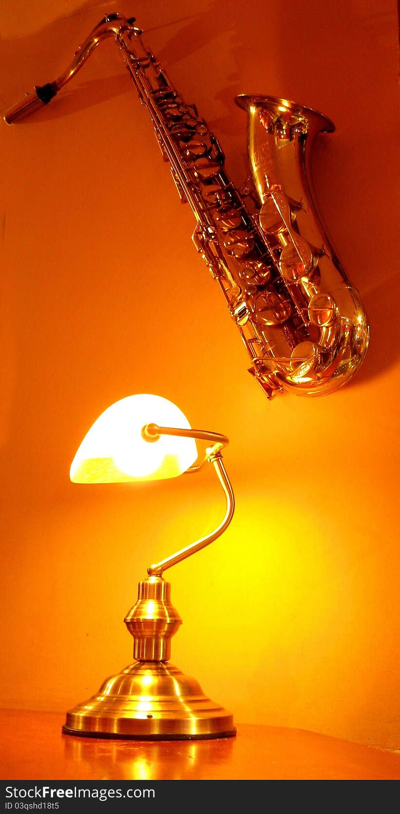 Saxophone on the orange wall next to lamp. Cafe decoration - indoor. Saxophone on the orange wall next to lamp. Cafe decoration - indoor