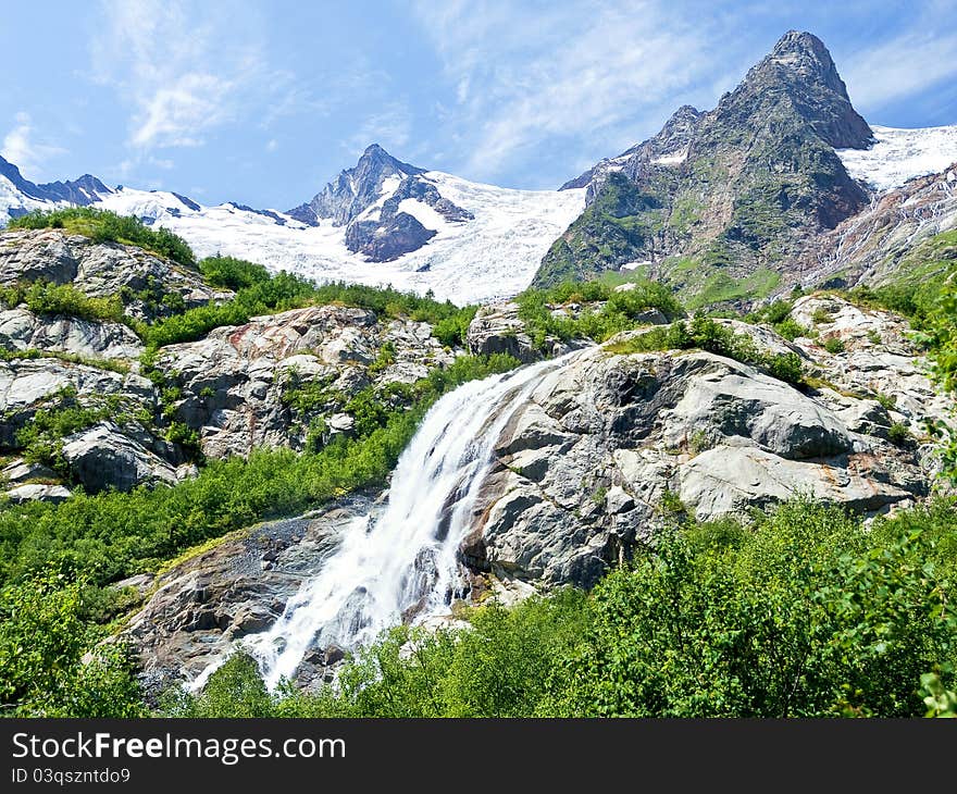 Huge waterfall among the rocky mountains covered with snow. Huge waterfall among the rocky mountains covered with snow