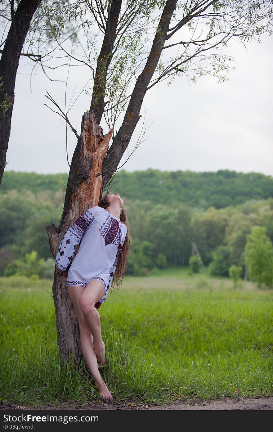 Portrait of sexy, lovely young girl in a beautiful national shirt standing next to a tree in an outdoor. Portrait of sexy, lovely young girl in a beautiful national shirt standing next to a tree in an outdoor