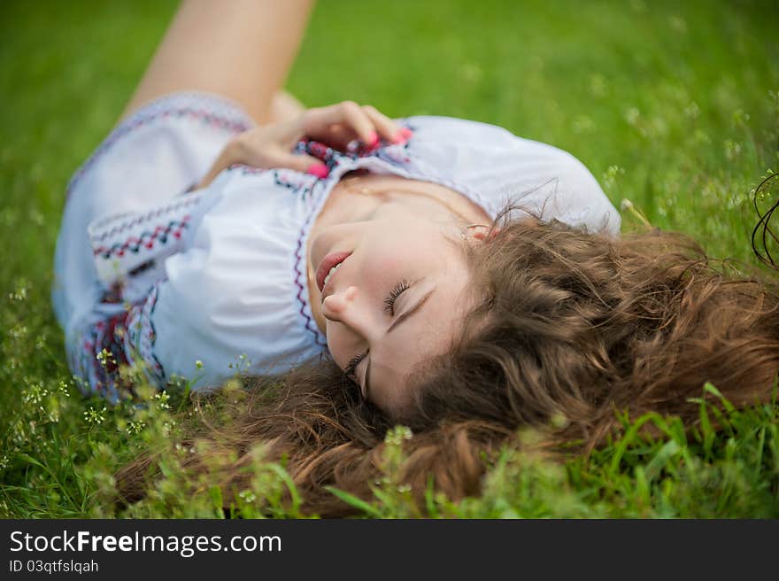 Portrait of a young sexually girl in the national shirt lying on the grass. Portrait of a young sexually girl in the national shirt lying on the grass