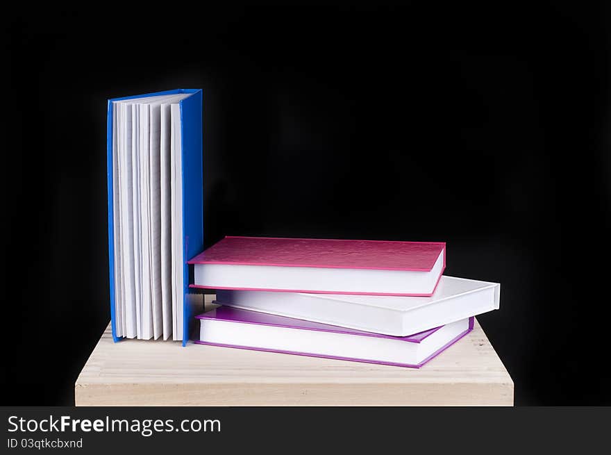 Four colorful books on a wooden table on a black background. Four colorful books on a wooden table on a black background