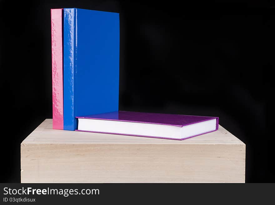 Three Colorful School Books On A Wooden Table