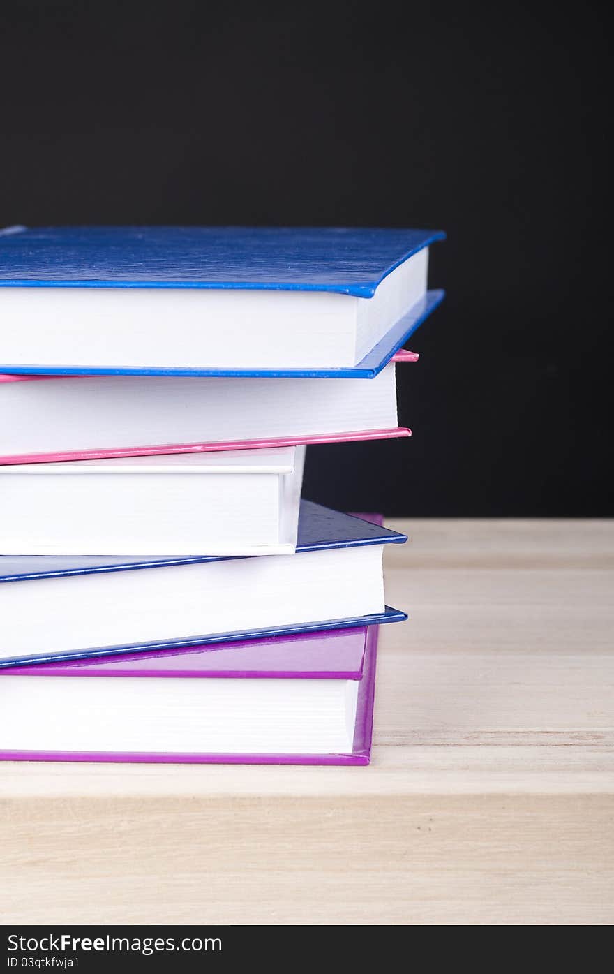 Pile Of Five Colorful Books On A Wooden Table