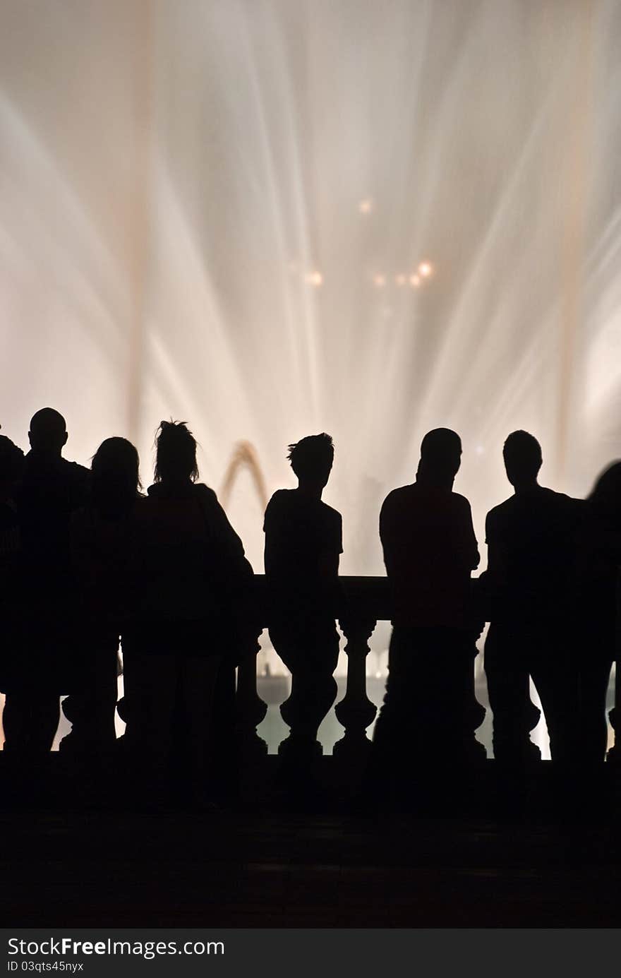 Some people's silhouettes in front of a fountain during an amazing show. Some people's silhouettes in front of a fountain during an amazing show