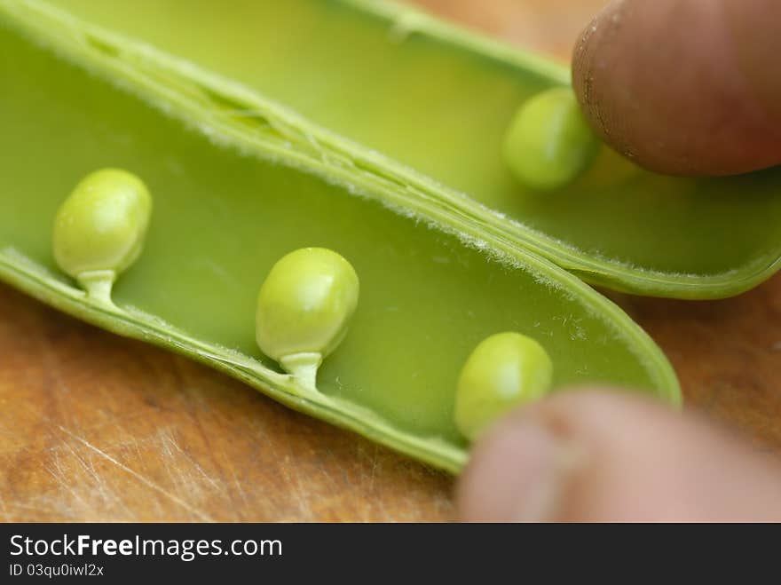 Peas in a pod arranged on a wooden chopping boar