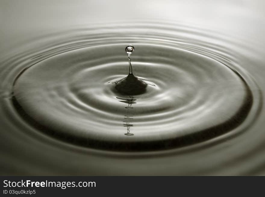 Water droplet and concentric ripples on a grey surface. Water droplet and concentric ripples on a grey surface.