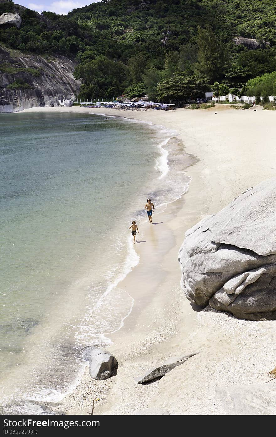 Two figures running on empty beach