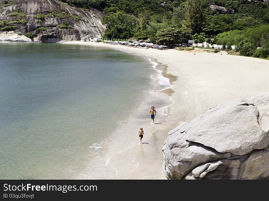 Two figures running on empty sandy beach. Two figures running on empty sandy beach