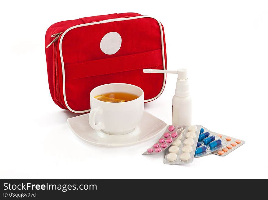 The image of the first-aid set, cup of tea with a lemon, tablets and an inhaler. The image of the first-aid set, cup of tea with a lemon, tablets and an inhaler