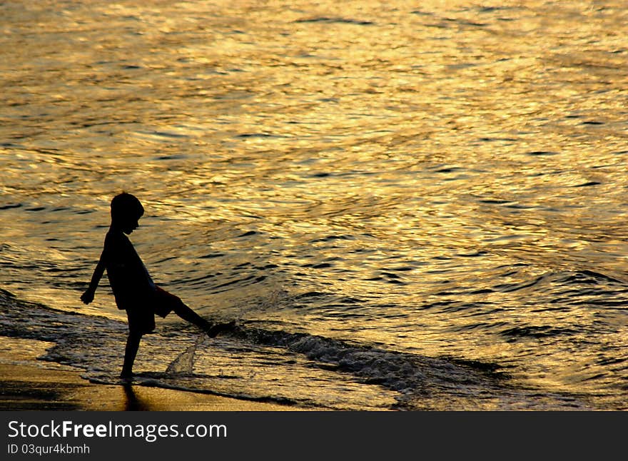 Contre jour image of a young boy playing by the sea shore. Contre jour image of a young boy playing by the sea shore