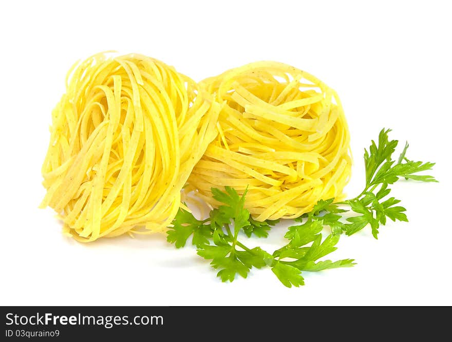 Two fettuccine pasta nests and green parsley on white background. Two fettuccine pasta nests and green parsley on white background